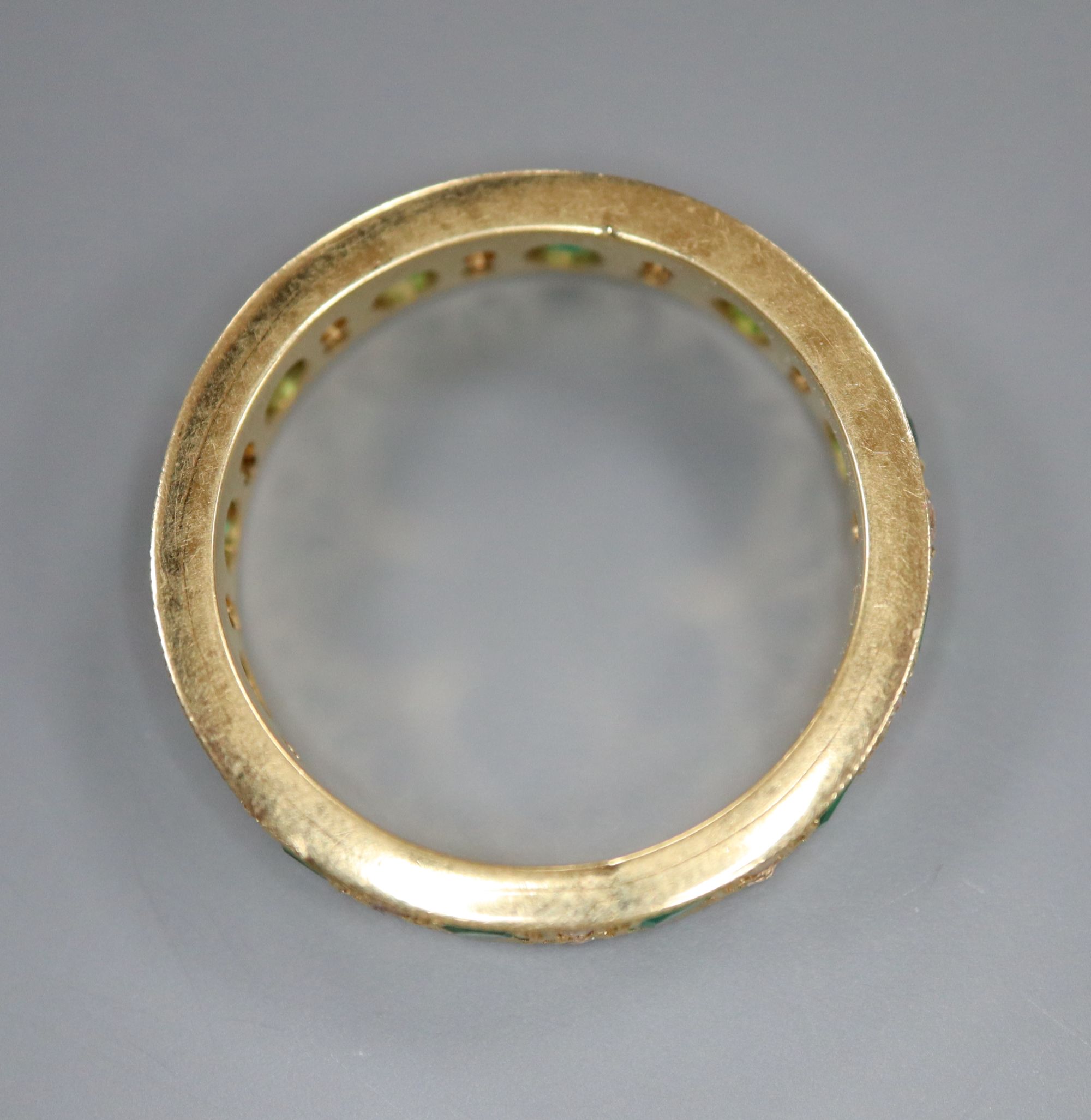 A mid to late 20th century yellow metal, emerald and diamond set full eternity ring, size P/Q, gross 5.7 grams.